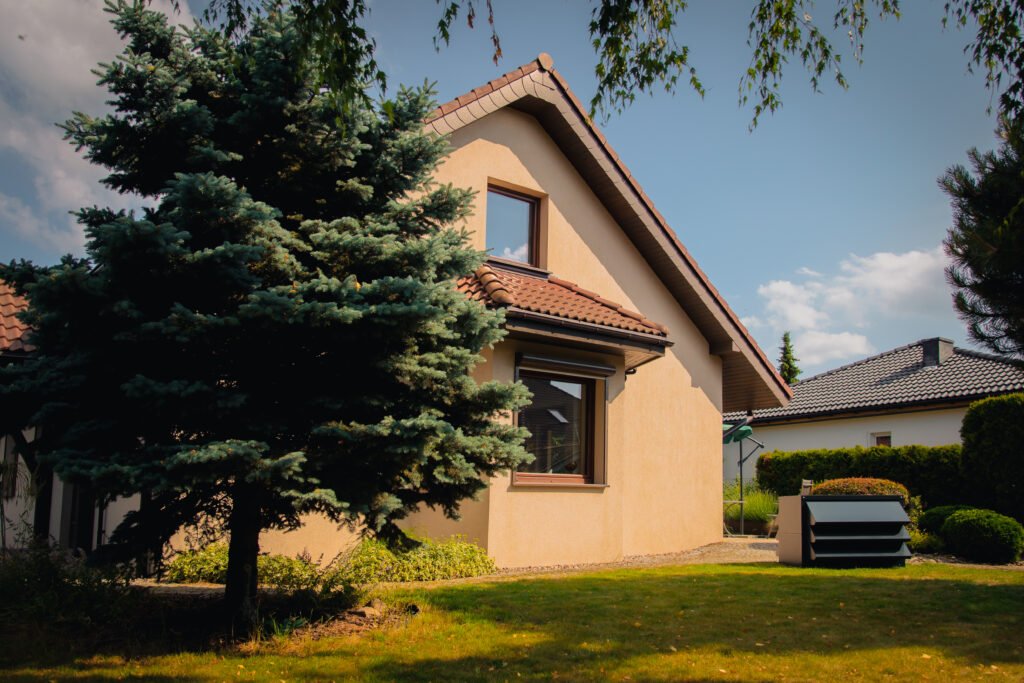 Freistehendes Einfamilienhaus, vor dem eine Wärmepumpe in einem schallgedämmten Gehäuse steht.