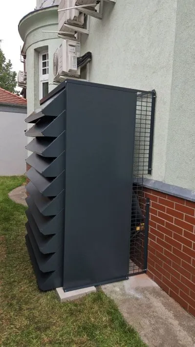 Hohe, anthrazitfarbene, maßgefertigte wärmepumpe schallschutzhaube
zum Schutz einer großen Wärmepumpe, die an der Gebäudewand montiert ist.