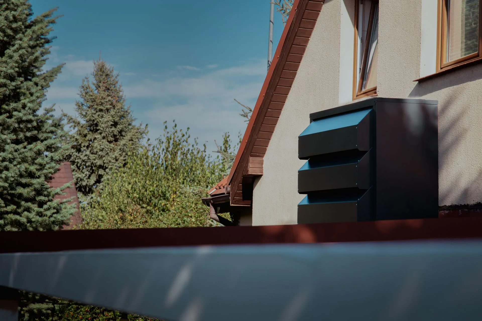 Dunkelgraues, lamellenförmiges Silencions-Akustikgehäuse für die Außeneinheit einer Klimaanlage, montiert an der Fassade des Gebäudes am Dach.