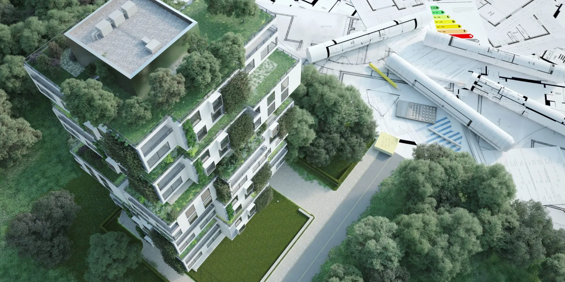 Visualisierung einer modernen Wohnsiedlung mit begrünten Dächern und Fassaden, von oben gesehen. Neben dem Gebäude liegen Architekturpläne, eine Papierrolle, ein Taschenrechner und Diagramme zur Energieeffizienz.